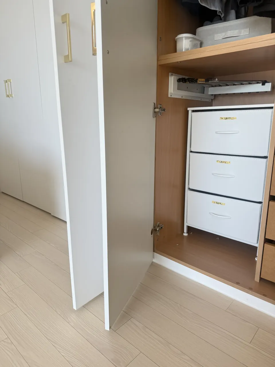 수리 전 경첩이 떨어져 열린 흰색 수납장 문